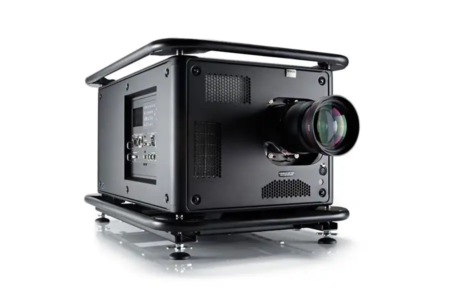 This image shows a high-performance black projector designed for professional use. It features a robust and industrial design with protective framing on the top and bottom. The projector has multiple ventilation grills for efficient cooling and a prominent, high-quality lens at the front for superior image projection. It includes various input/output ports on the side, suitable for advanced connectivity options. The projector is supported by adjustable feet, ensuring stability and proper alignment. The sleek, matte black finish emphasizes its professional and durable build.