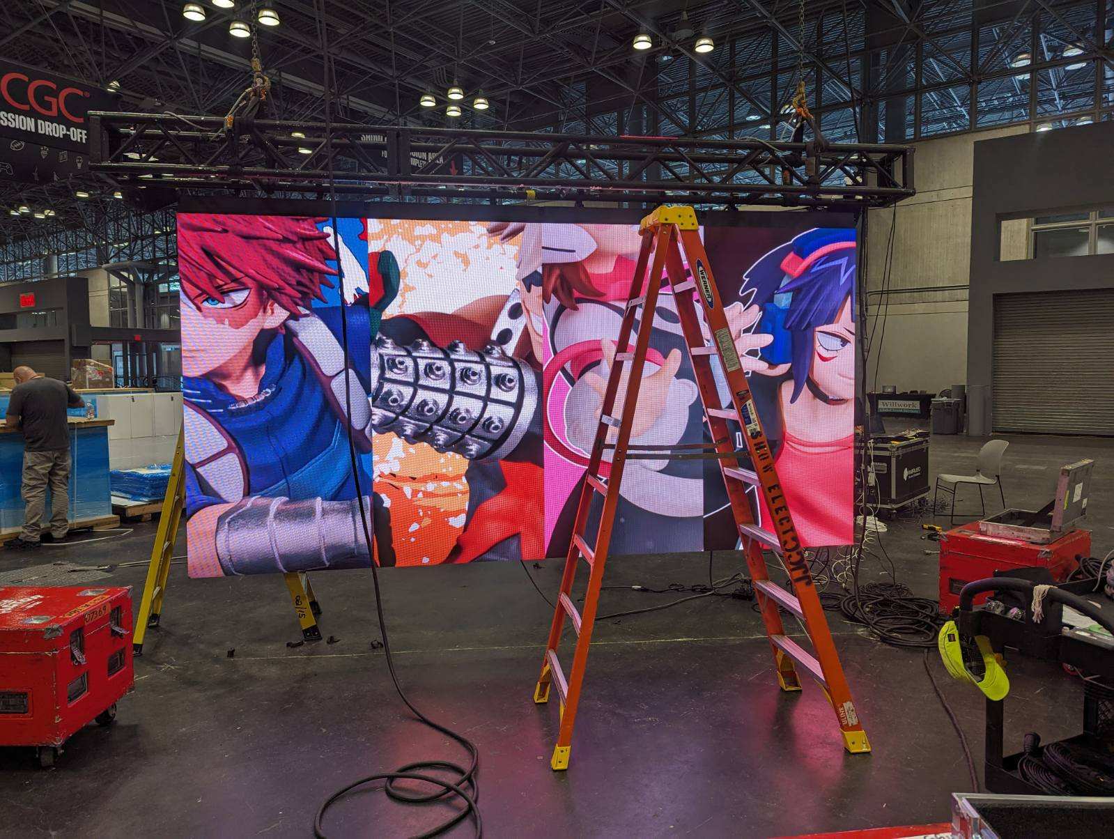 Technicians assembling LED video wall with animated graphics at a trade show booth