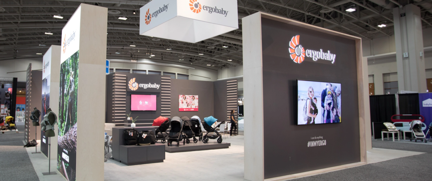 Monitor rentals at a trade show booth displaying branded content on large digital displays.