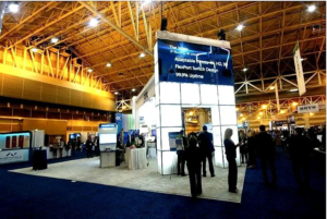 Here’s a trade show booth in a big convention center. AVR Expos LED video wall rental is front and center with info on adaptable inputs, HD, 3G, FlexPort Switch Design and 99.9% uptime. People are talking to exhibitors and checking out displays and presentations. The room is full of other booths and banners, it’s a typical trade show environment. High ceiling and lots of light makes it feel open and welcoming. If you are looking for AV rentals in Virginia for your event AVR Expos has you covered.