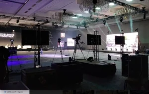 Indoor event setup in Atlanta with audio visual equipment, including cameras, screens, lighting, and staging for a professional presentation