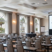 A high-lumen, ceiling-mounted laser projector shining onto a large, crisp projection screen in a well-lit Orlando hotel ballroom for a corporate presentation.