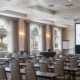 A high-lumen, ceiling-mounted laser projector shining onto a large, crisp projection screen in a well-lit Orlando hotel ballroom for a corporate presentation.