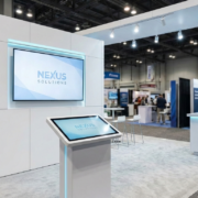 Minimalist trade show booth using a single large monitor and touchscreen to reduce AV rental costs.